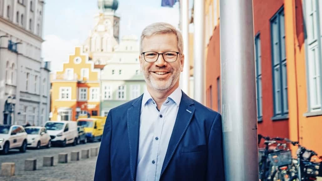 Portraitfoto von Stefan Fassbinder, vor Greifswalder Rathaus, im Hintergrund verschwommen Greifswalder Dom